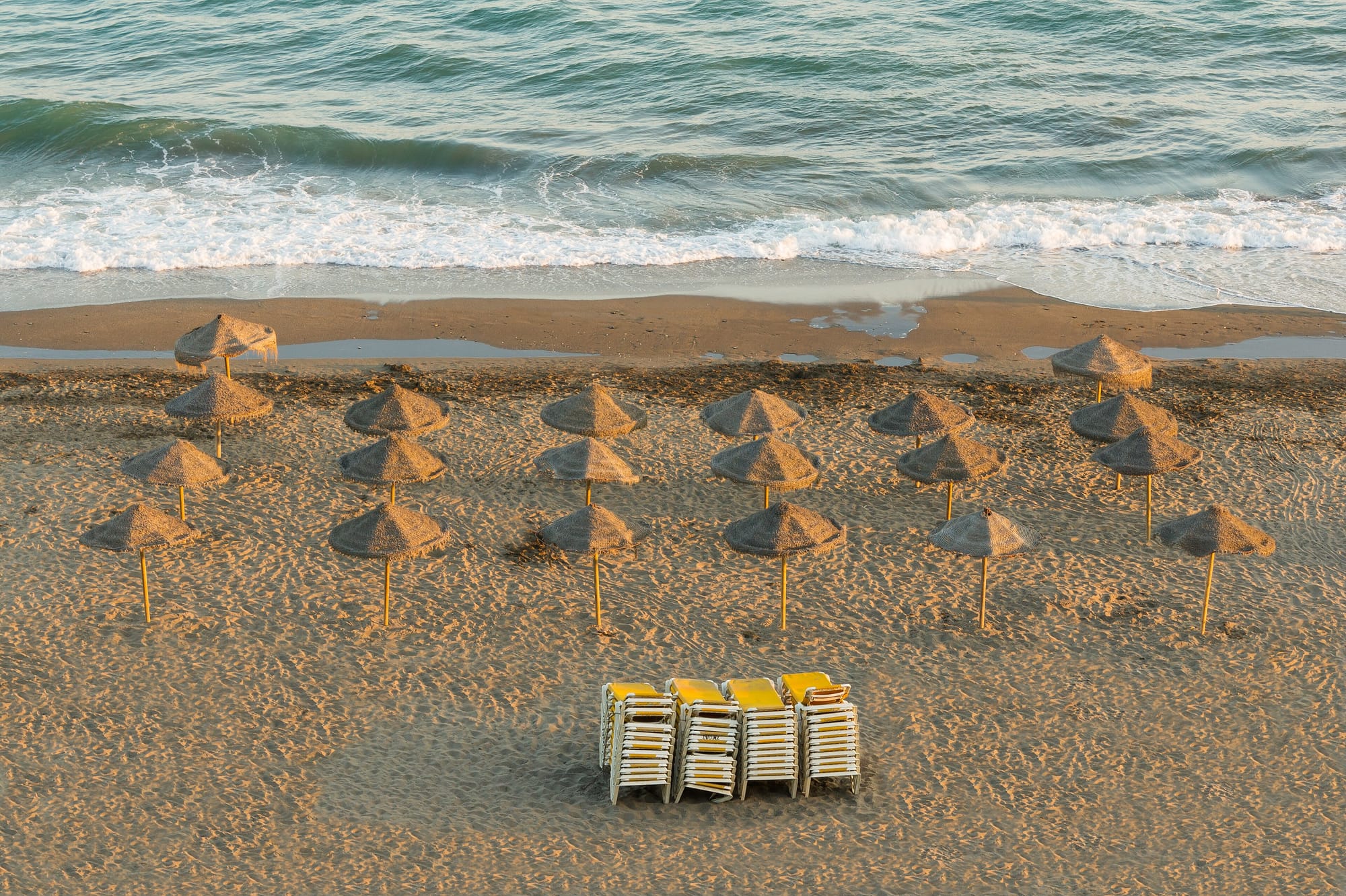Golden evening light on empty straw parasols, Rincón de la Victoria