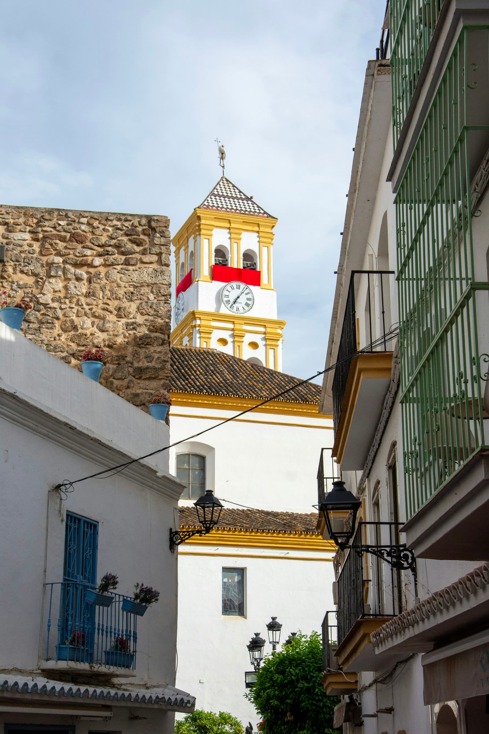 Marbella's old town clock tower seen down a narrow whitewashed street