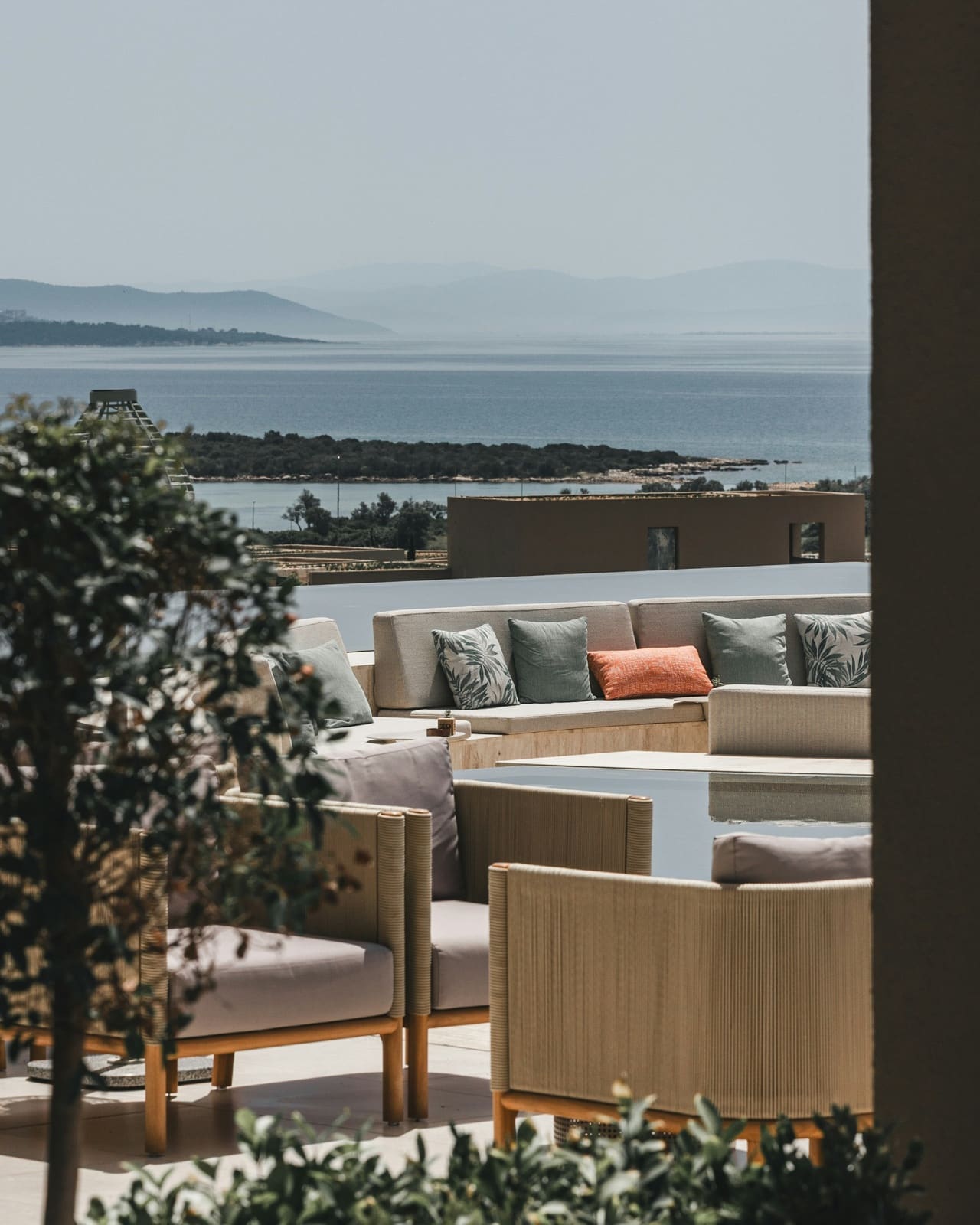 Een terras met een bank en uitzicht over zee en een wit dorp in de schemering