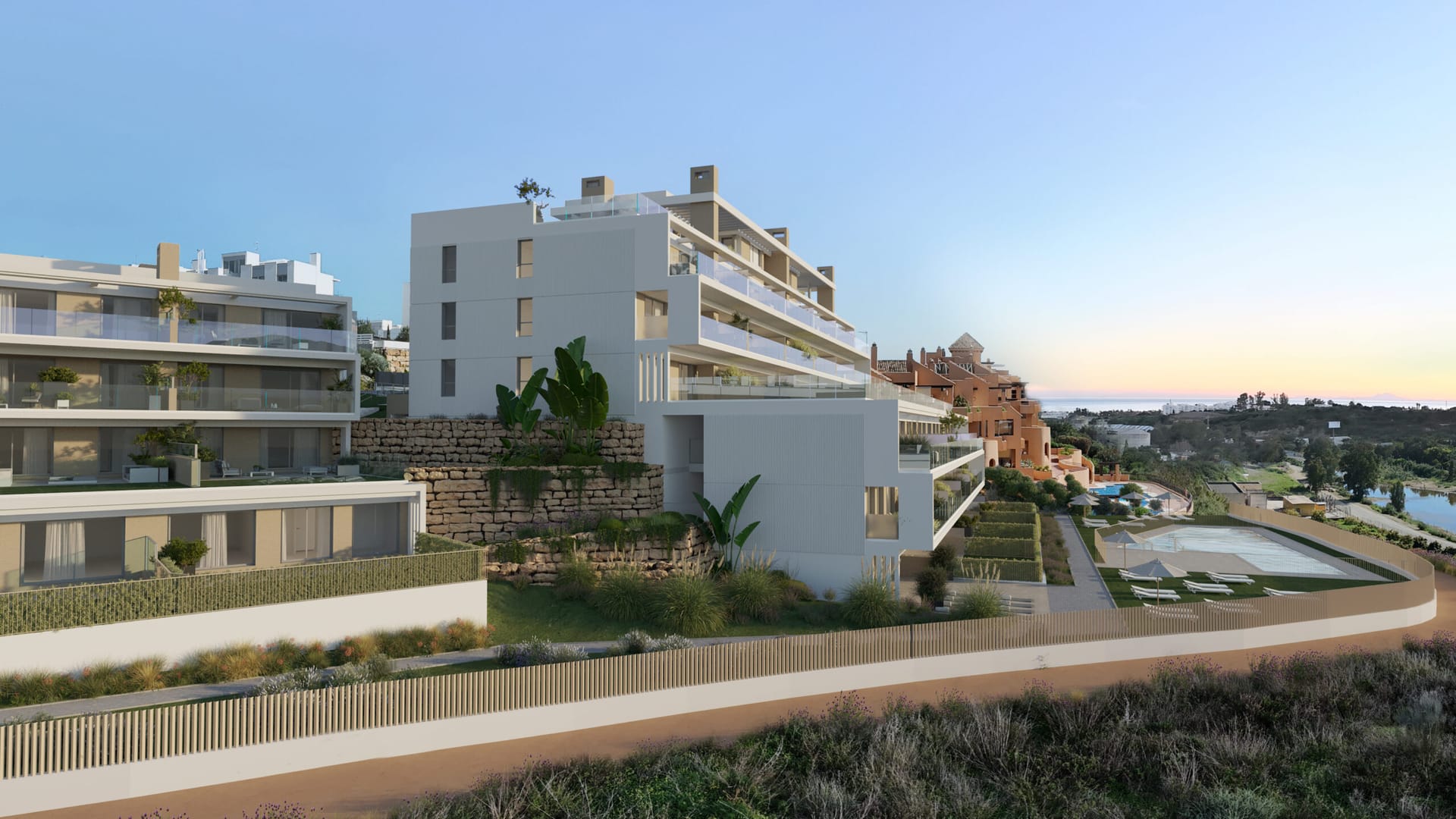 The buildings at dusk, set into the slope above the pool, with the coast in the distance. Aire, Cancelada, Estepona.