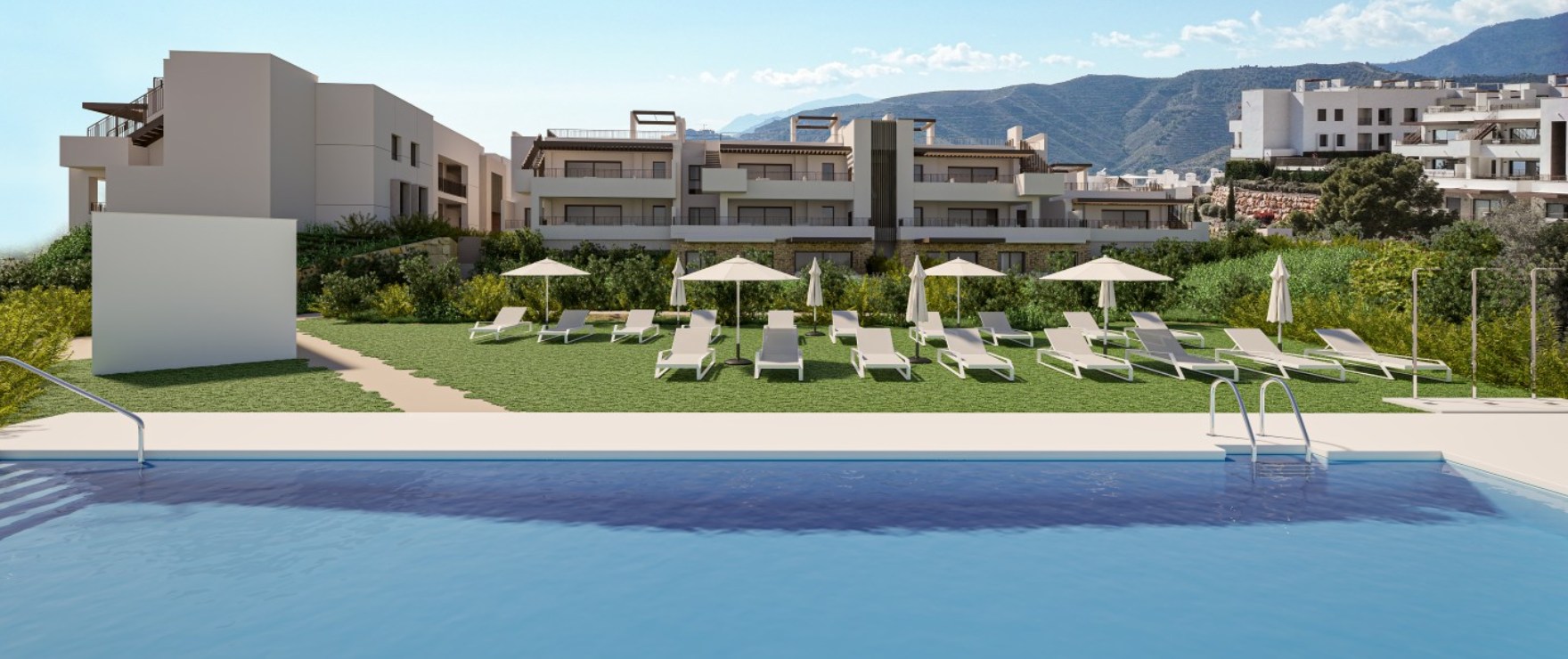 The pool and its lawn, with loungers and parasols and one of the buildings behind. Almazara Gardens, Cerros del Lago, Istán.