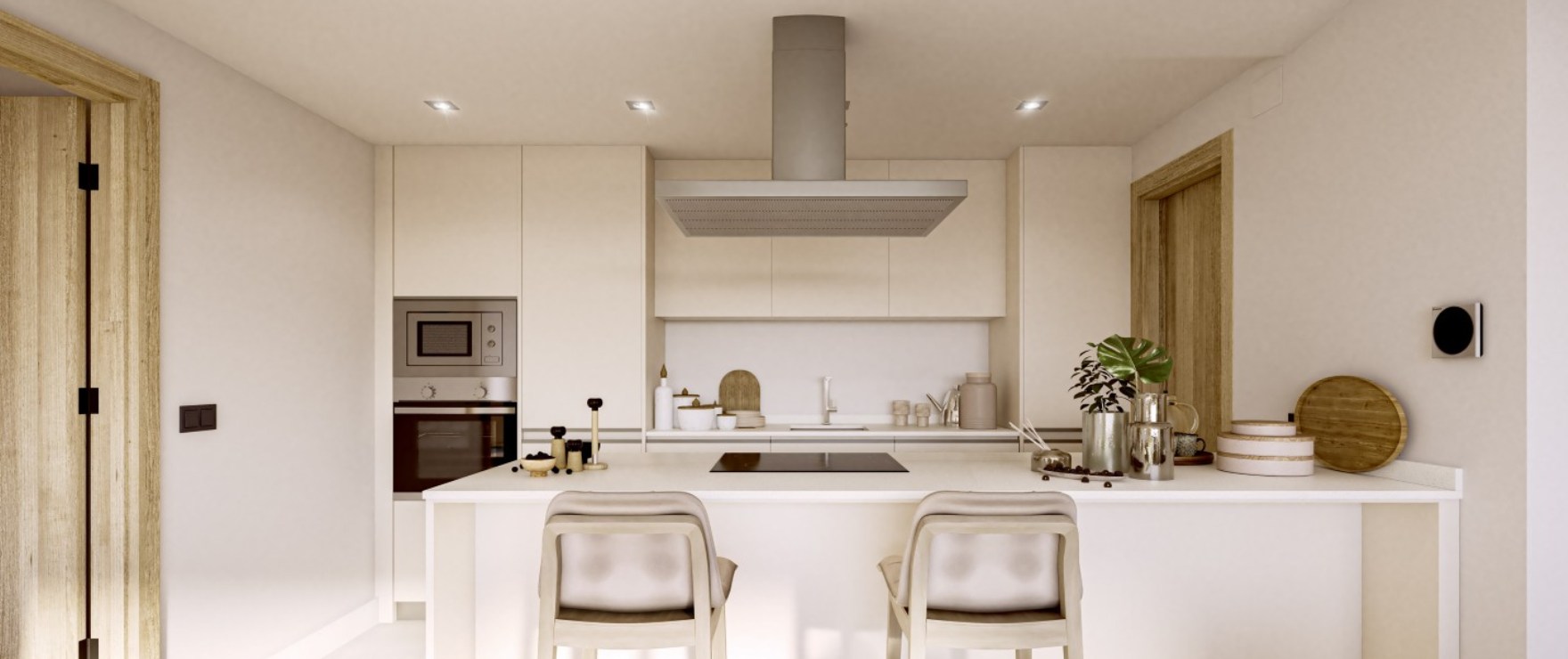 The kitchen in white, with the oven and microwave set into a tall unit and stools at a breakfast bar. Almazara Gardens, Cerros del Lago, Istán.