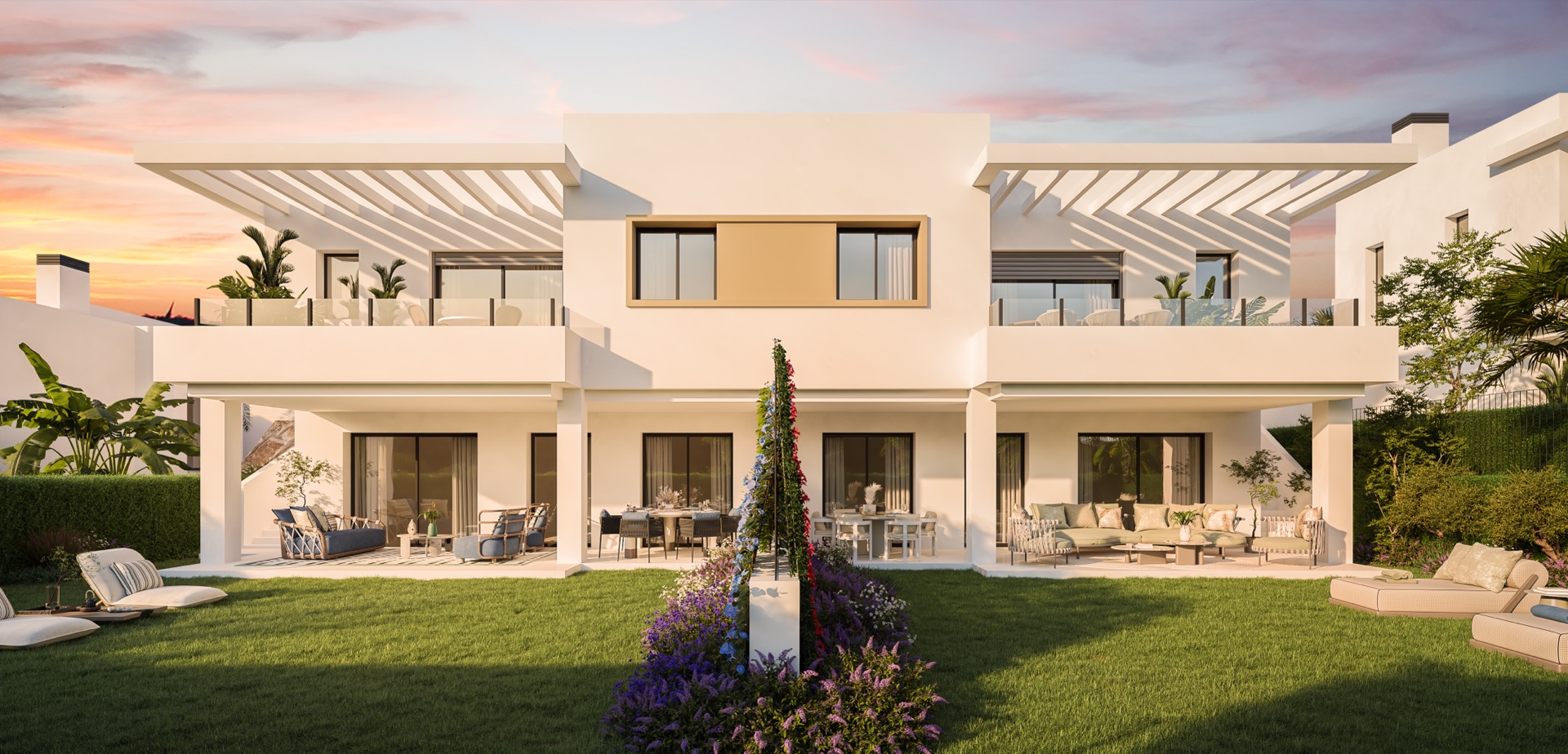 A pair of the semi-detached houses at dusk, with covered terraces opening onto the lawn. Apron Estepona, Estepona Golf, Estepona.