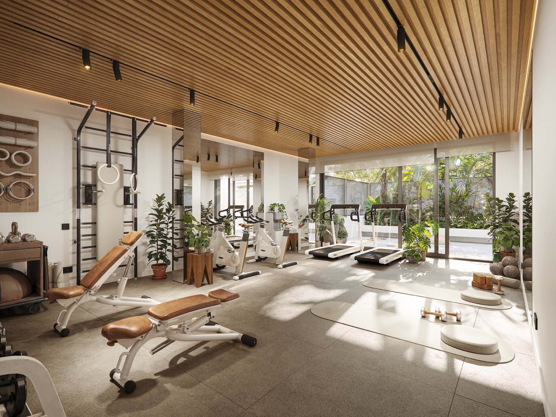 The gym, with cardio machines, free weights and a rack of gymnastic rings, opening onto the gardens. Azure Living, Avenida del Mediterráneo, Torre del Mar.