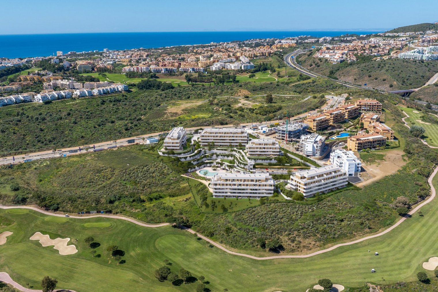 The new development from the air, its buildings stepped down the hillside above the fairways, with La Cala de Mijas and the sea beyond. Cala Swing, La Cala de Mijas, Mijas.