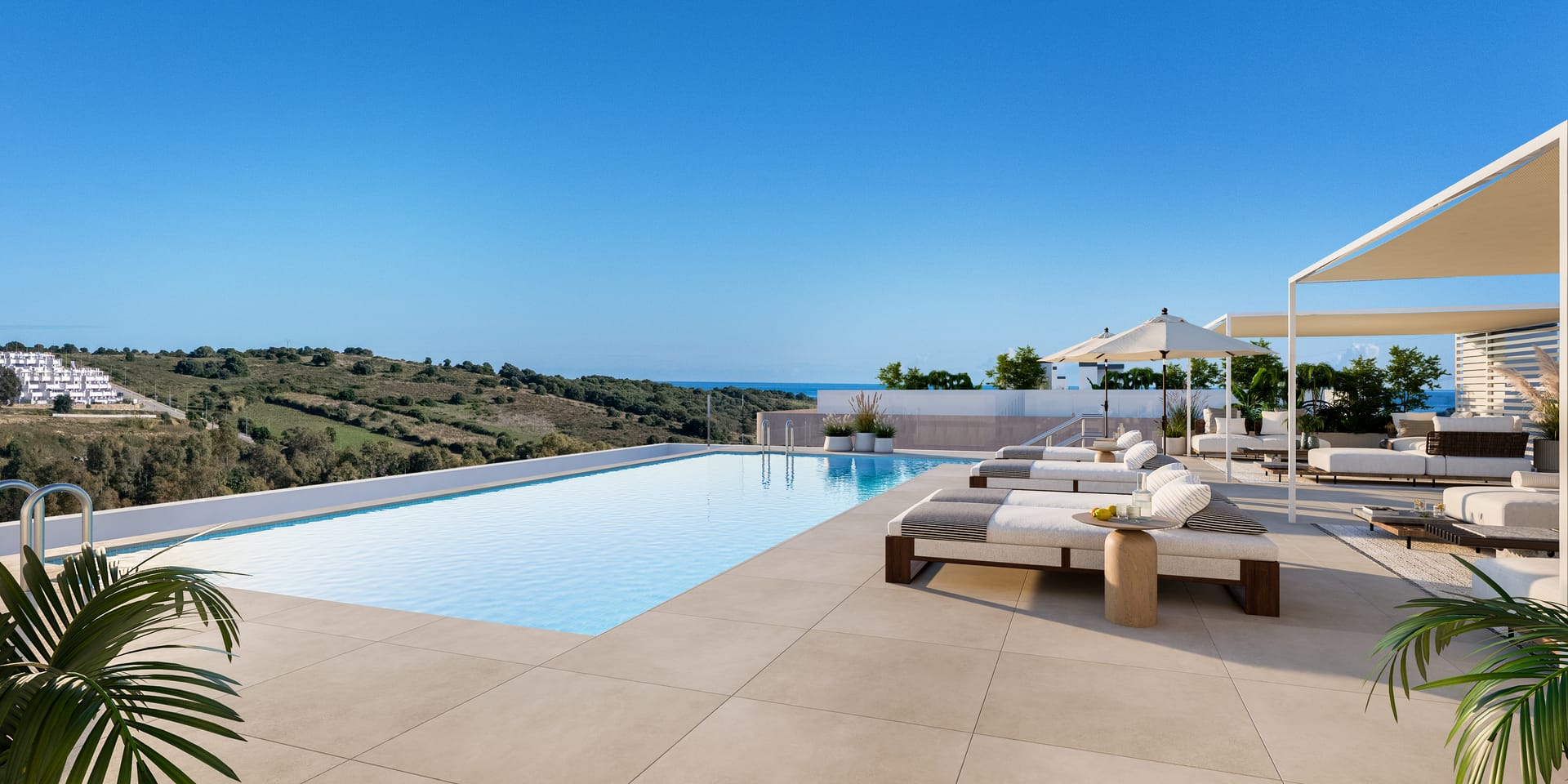 The rooftop pool, with sun loungers along its edge and the sea in the distance. Eagle Hills Estepona, Estepona Golf, Estepona.