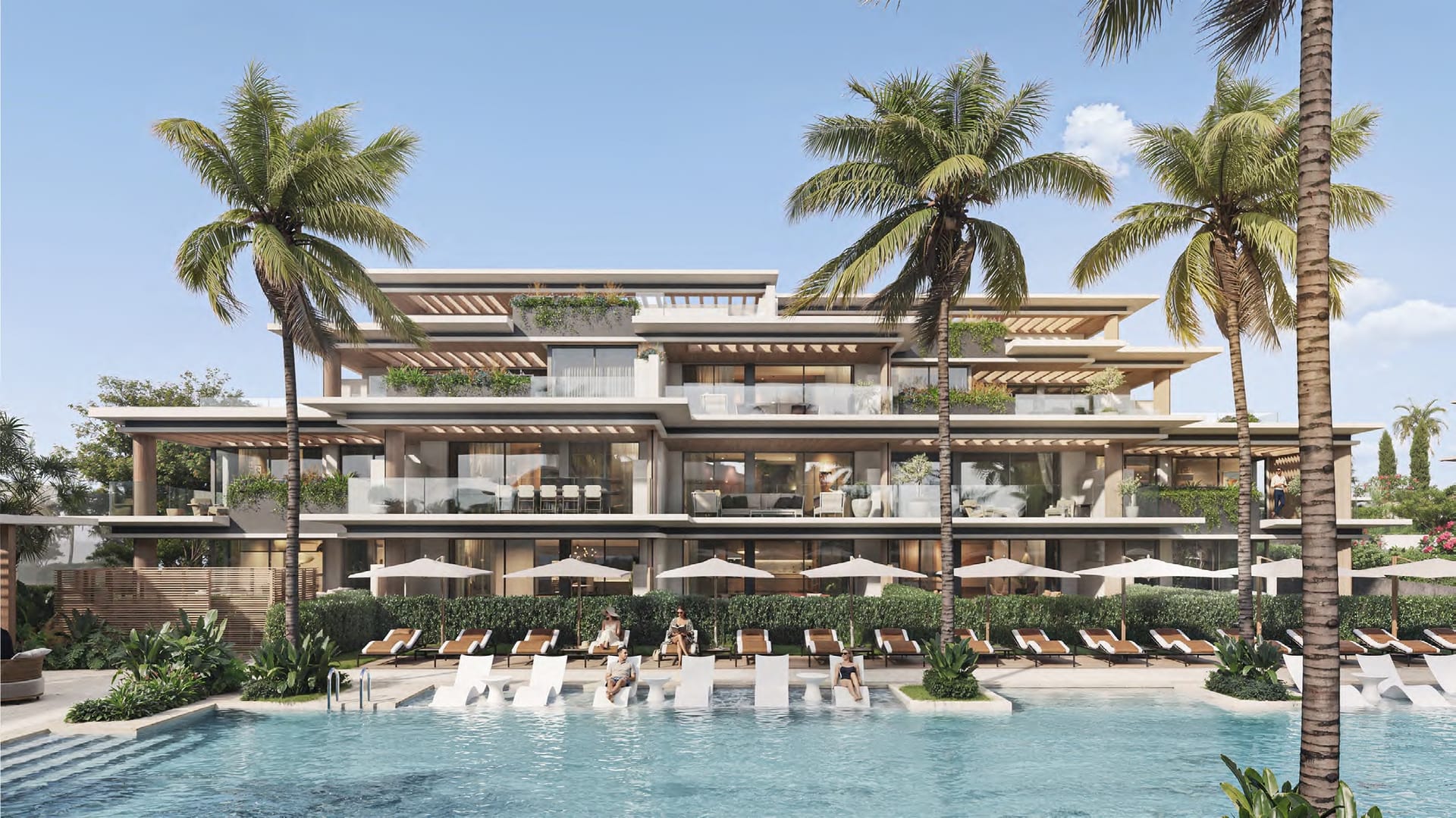 The outdoor pool, with loungers set in its shallow edge and palms in front of the buildings. Essence Residence, Cancelada, Estepona.