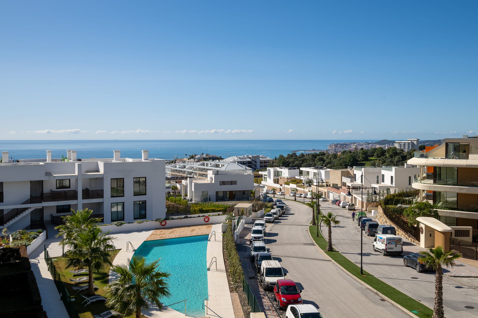 The pool seen from a terrace above, with the street and the coast beyond. Horizon 36, El Higuerón, Fuengirola.
