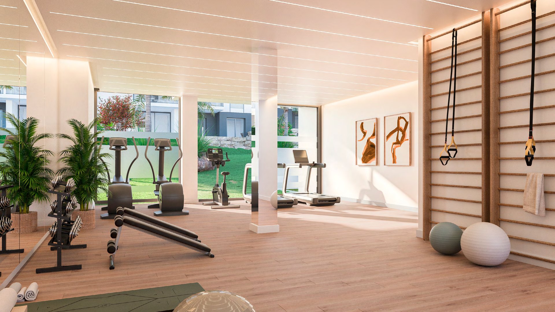 The gym, its machines and wall bars set against a window that looks onto the garden. Isidora Living, Calle Carlos Cano, Estepona.