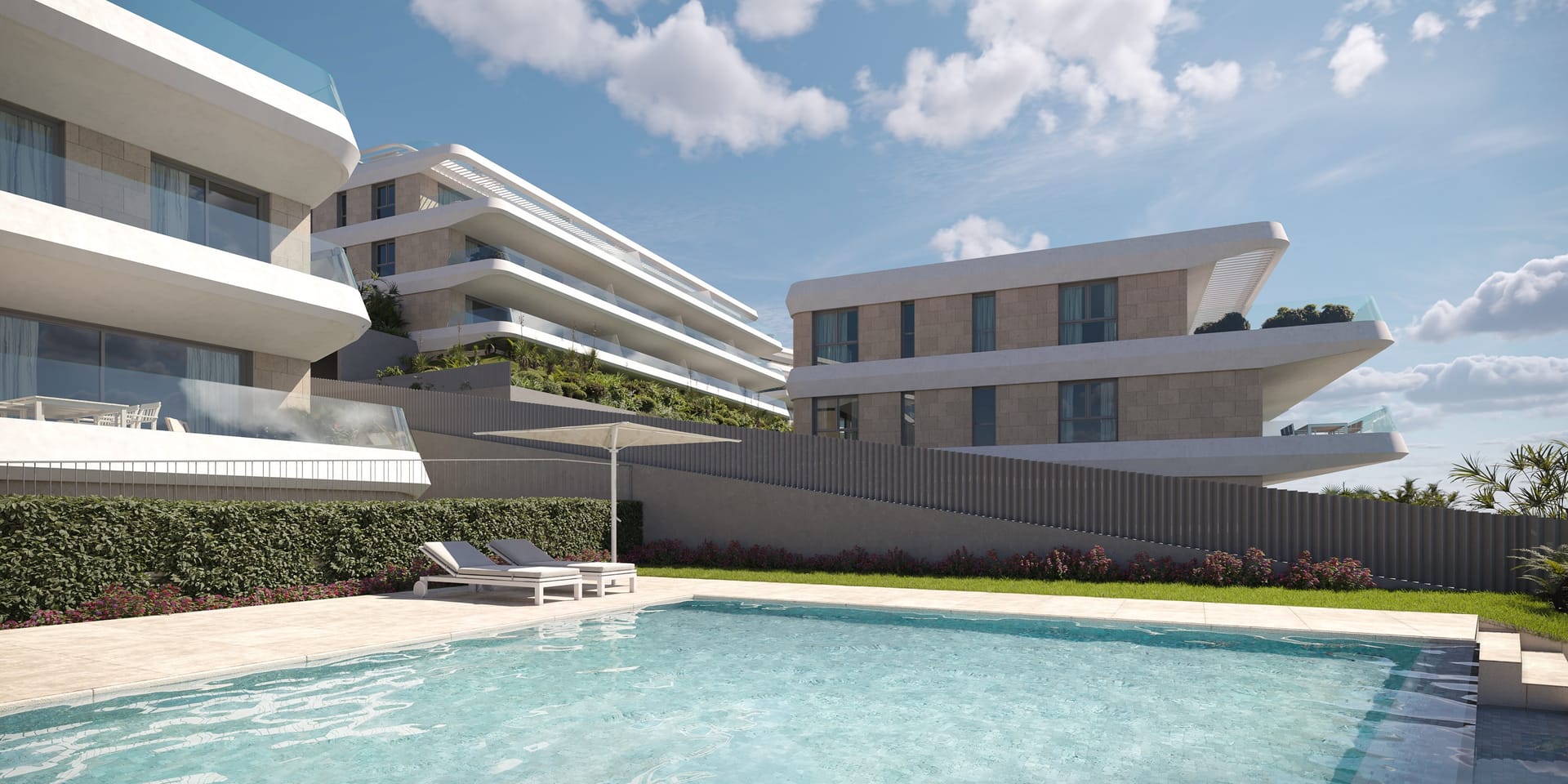 The pool between the buildings, with two loungers under a parasol and a hedge along the lawn. Libella, La Resina, Estepona.
