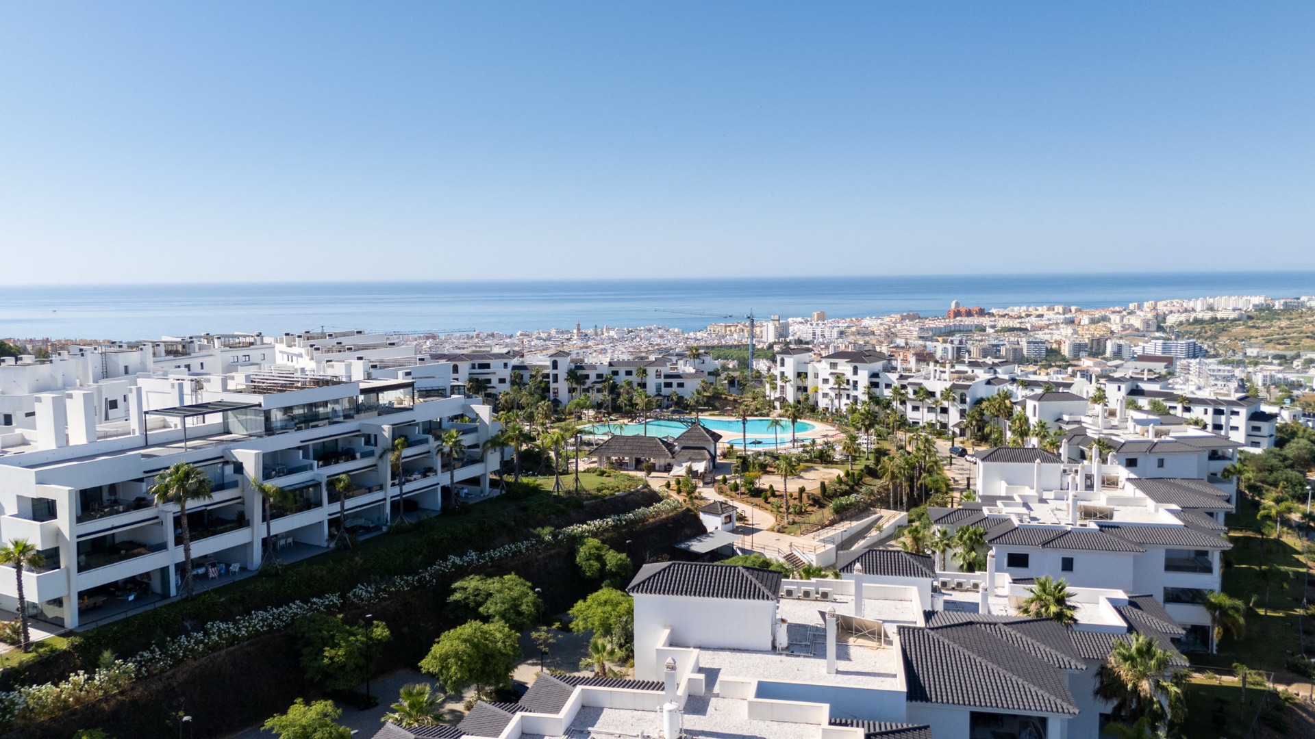 One of the resort’s pools, set among palms, with Estepona and the sea beyond. Mirador de Estepona Hills, Altos de Estepona, Estepona.