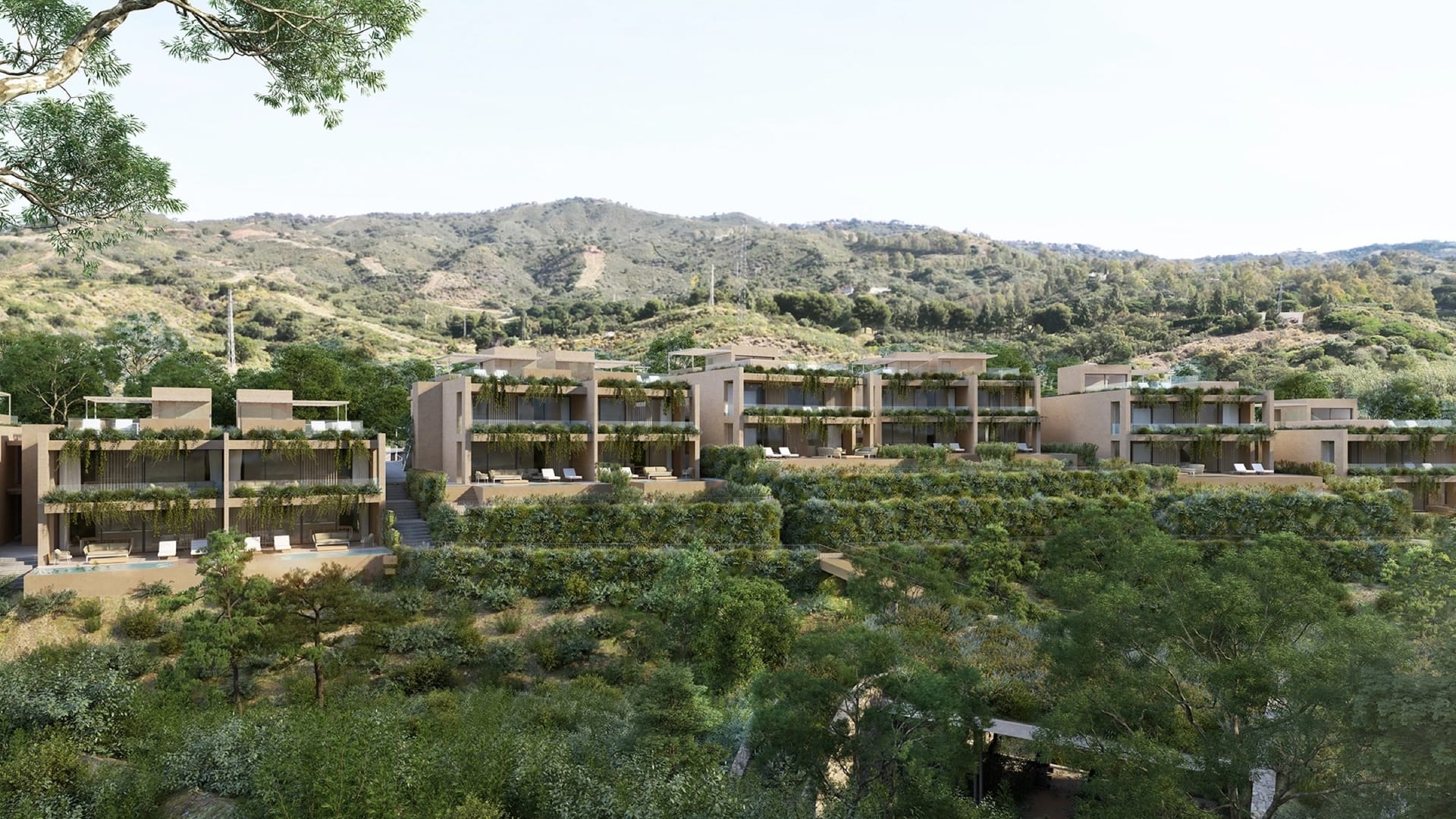 The buildings set among trees in the valley, with the hills behind. Sira Homes, Elviria, Marbella.