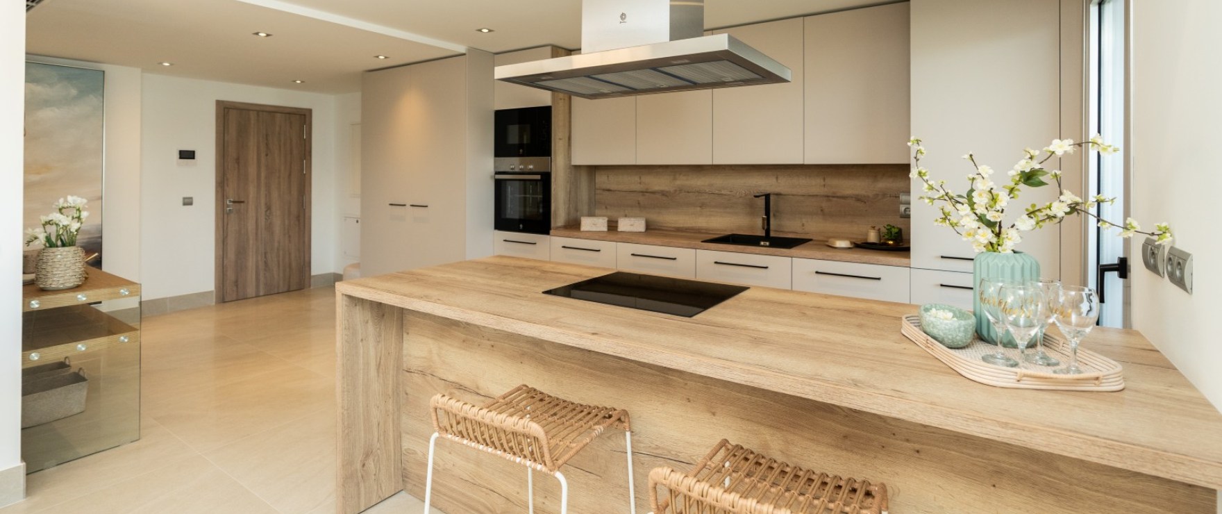 The kitchen, with a wood-effect worktop over a peninsula, an induction hob and the oven and microwave in a tall unit. Solana Village, La Cala Golf, Mijas.