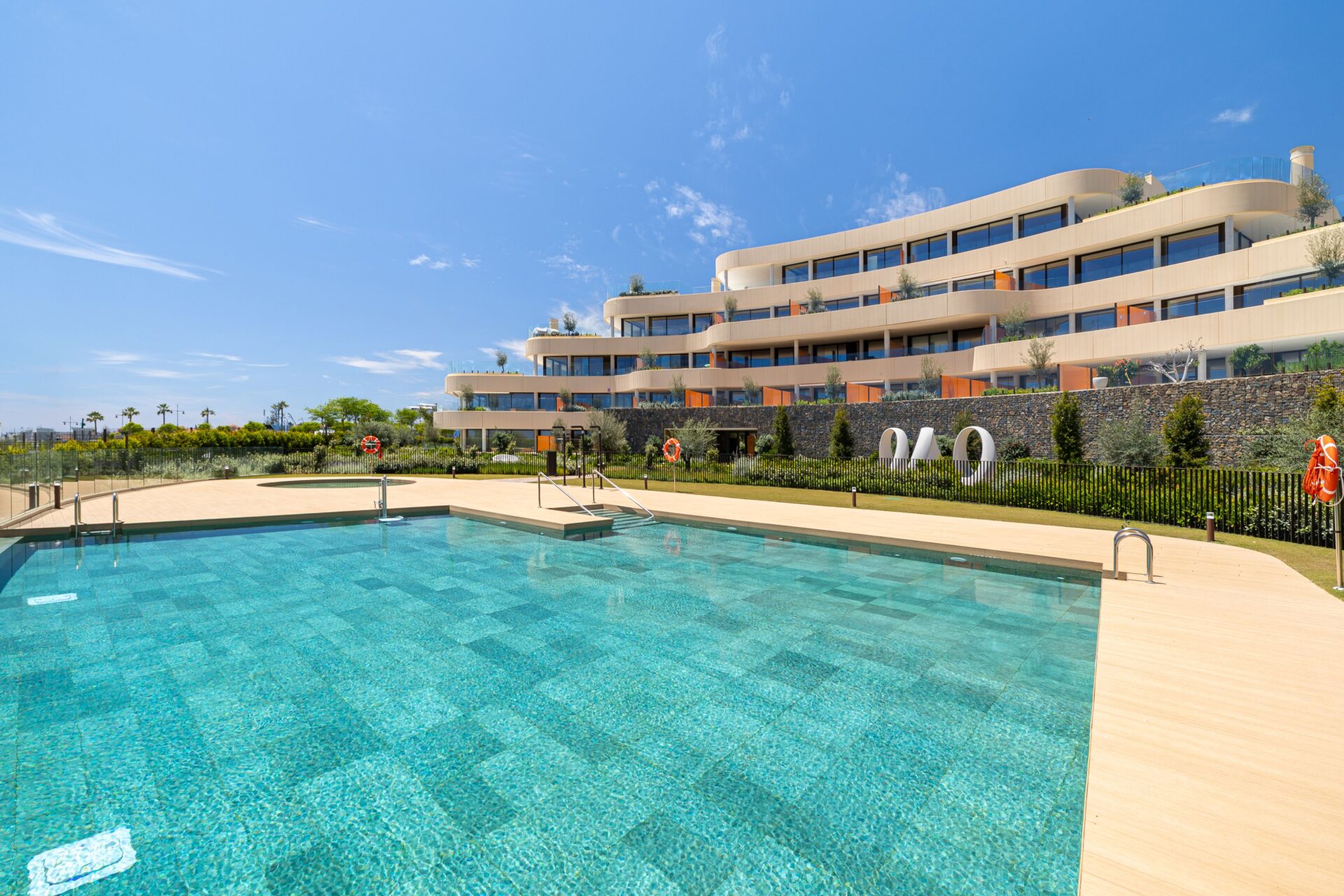 The pool in the gardens, with the curved buildings rising behind it. South Residences, El Higuerón, Fuengirola.