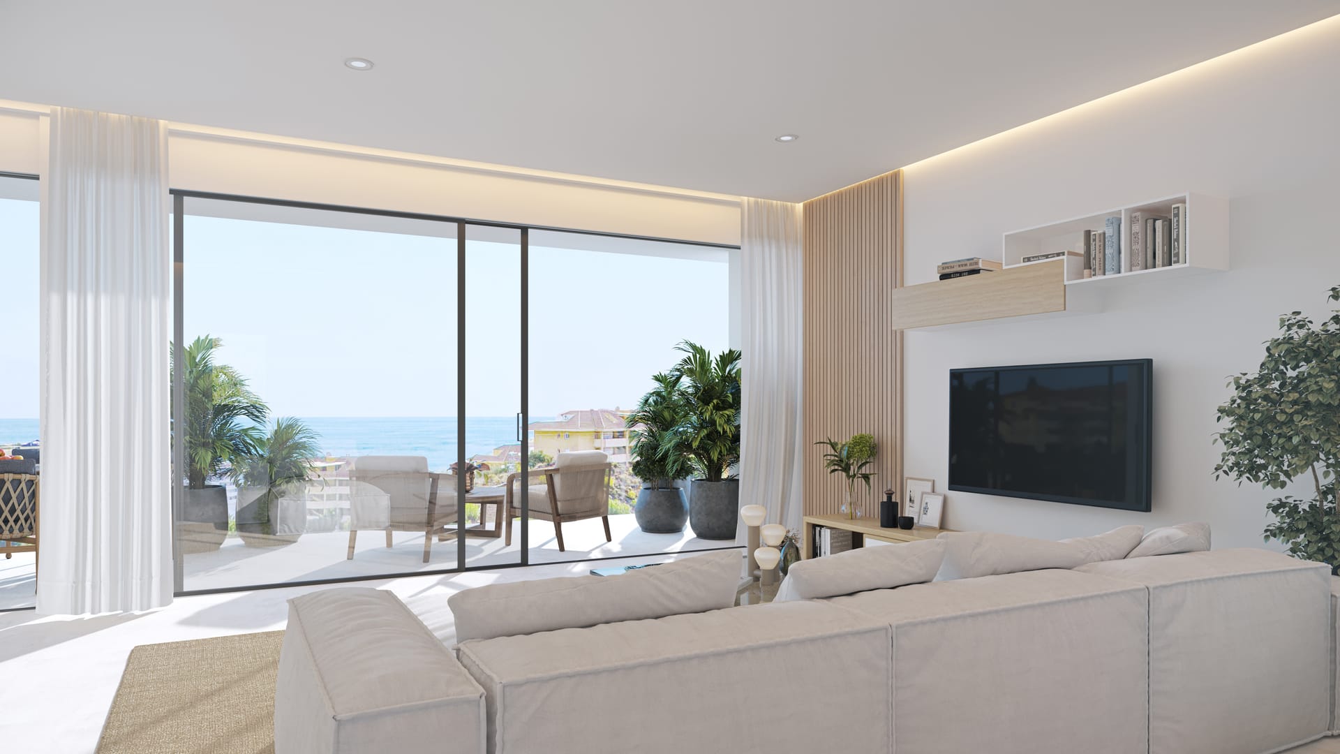 A living room with a glass wall that slides back onto the terrace, and the sea beyond it. The Kos, El Higuerón, Fuengirola.