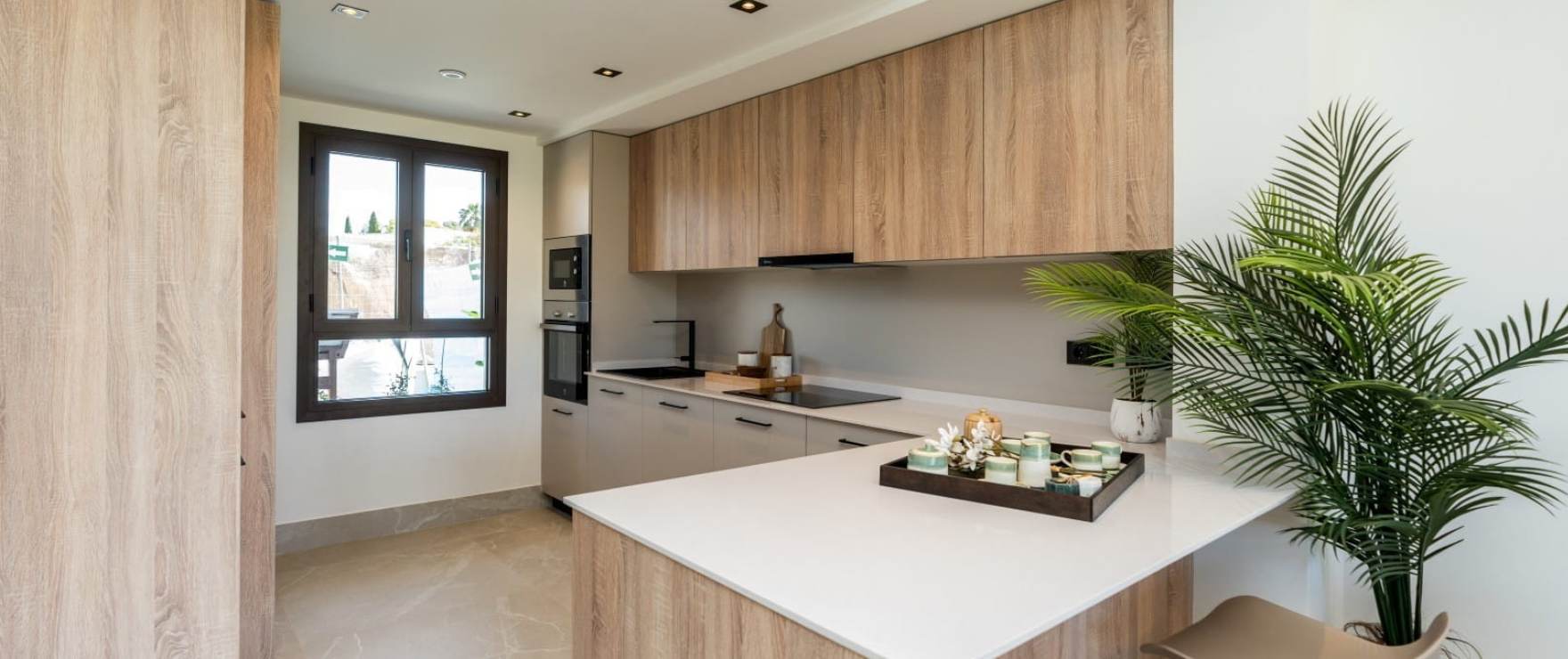 The kitchen, with oak units along the wall and a white peninsula. The Meadows, La Cala Golf, Mijas.