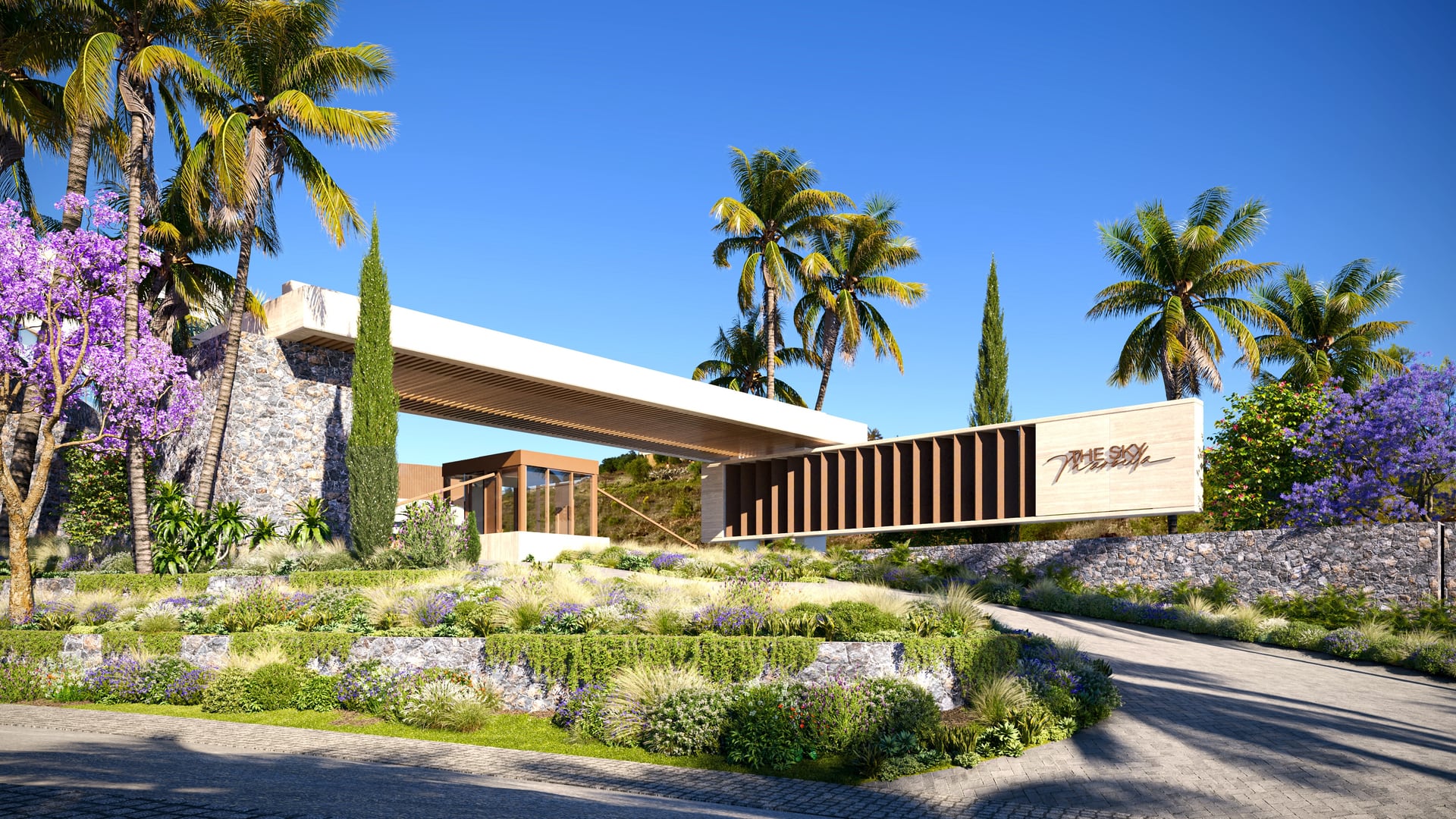 The entrance, with a glazed pavilion under a long flat roof, the development’s name on a slatted timber wall, and palms and flowering jacaranda around it. The Sky Marbella, La Alborada, Benahavís.