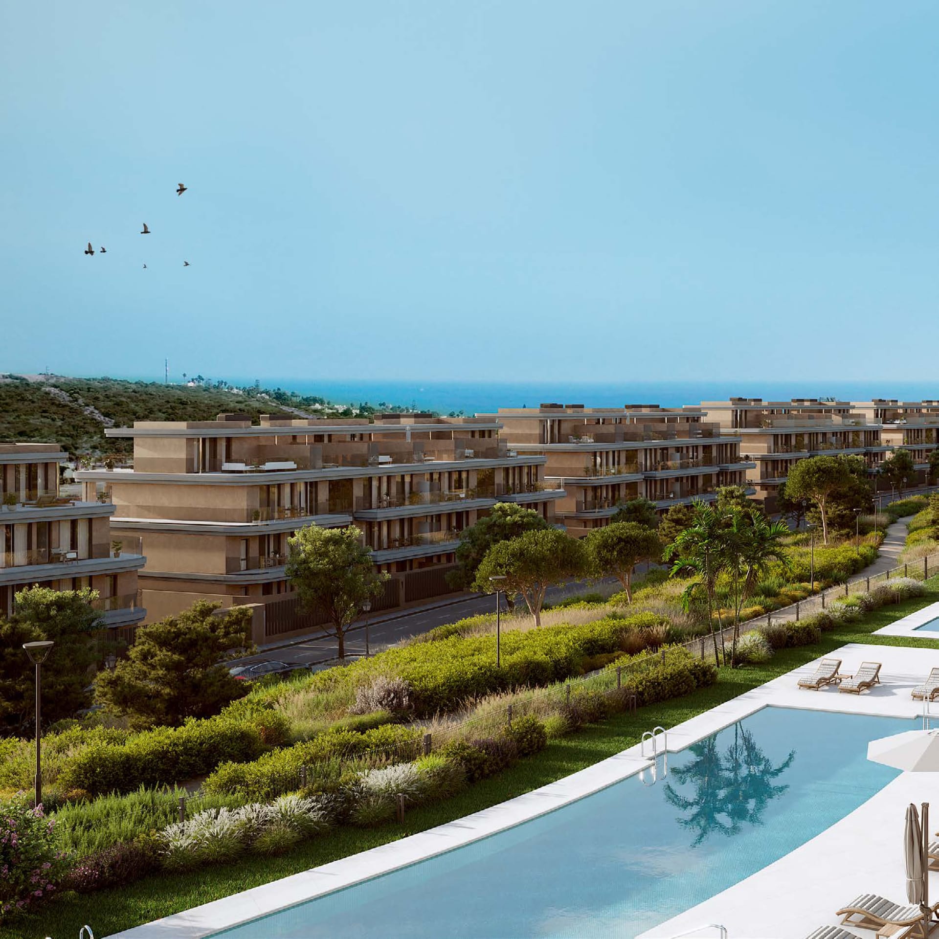 Gardens and the outdoor pool in front, with the buildings beyond and the sea on the horizon. Unika I, Buenas Noches, Estepona.