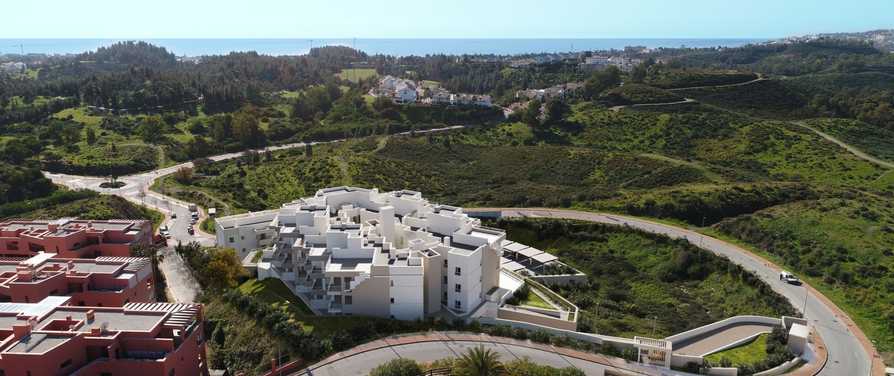 An aerial view of the buildings and their pool, with the hills behind and the sea on the horizon. Valley Views, Hipódromo, Mijas.