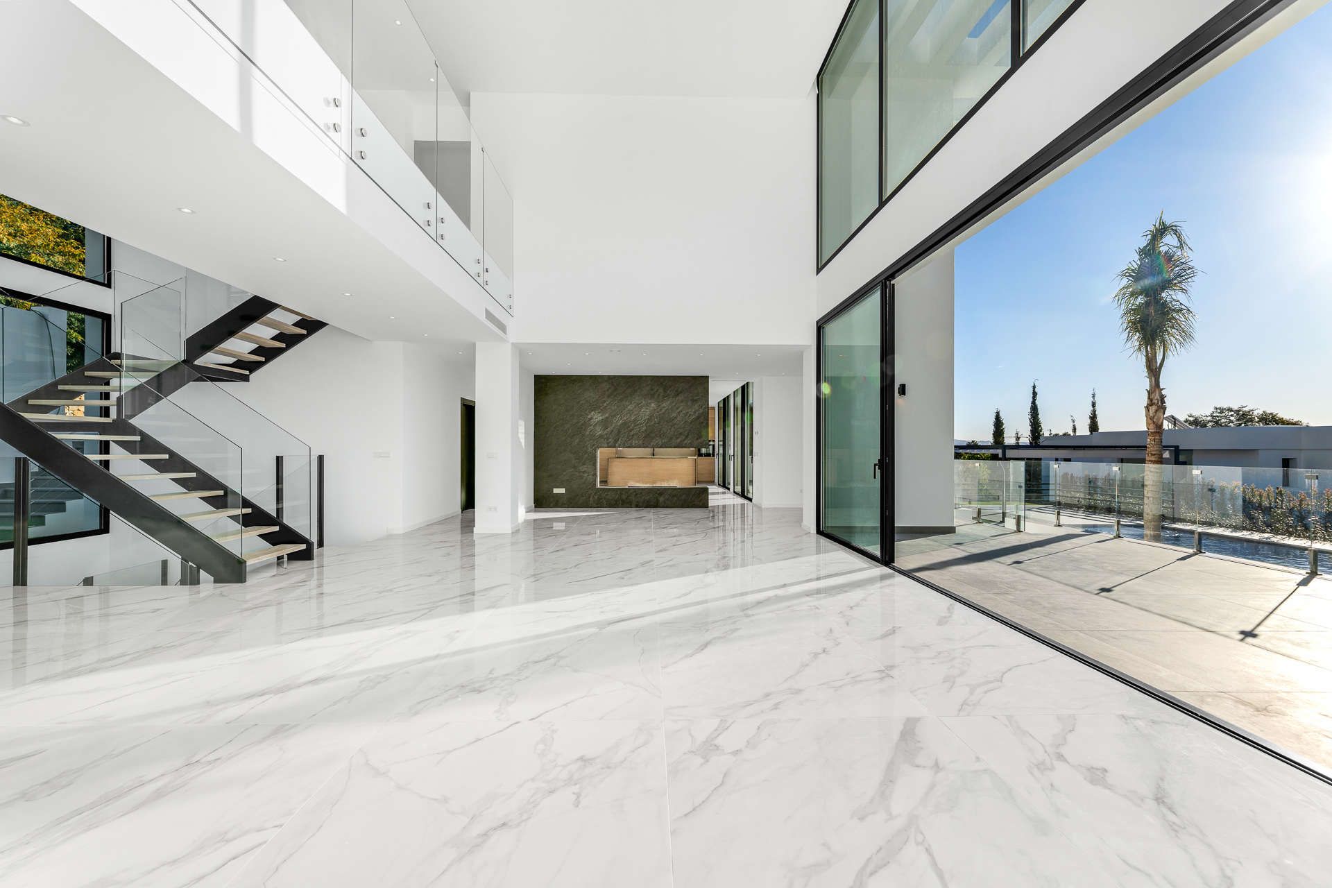 The living room of the finished villa, rising through two floors with a glass wall onto the terrace. Villa Paradise, Paraíso Alto, Benahavís.