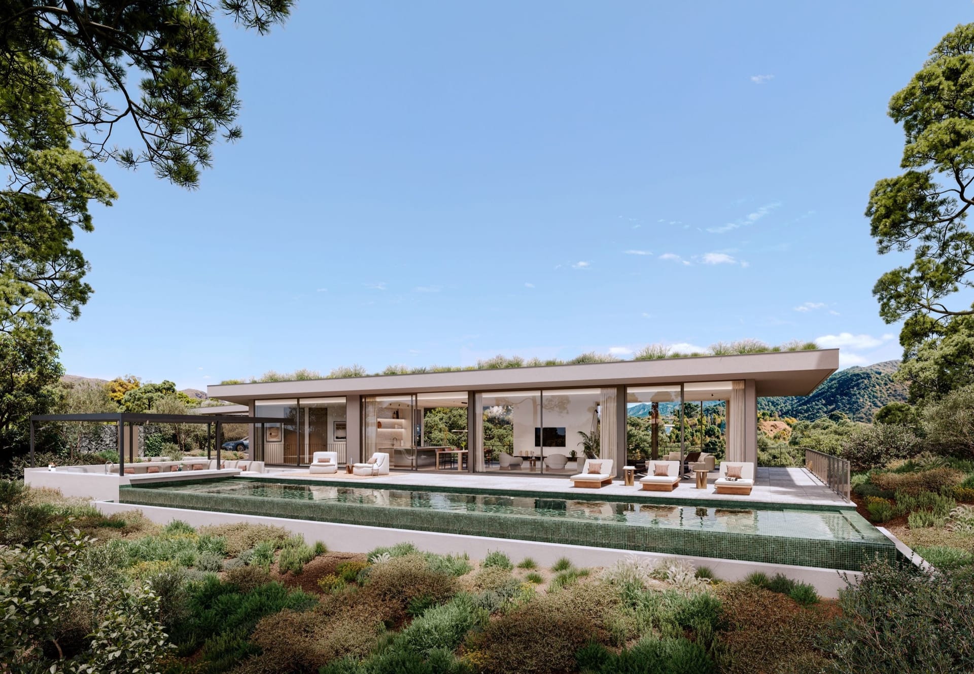 A long pool along the front of a villa, with loungers on the terrace and pines around it. Vitae Villas, Monte Mayor, Benahavís.
