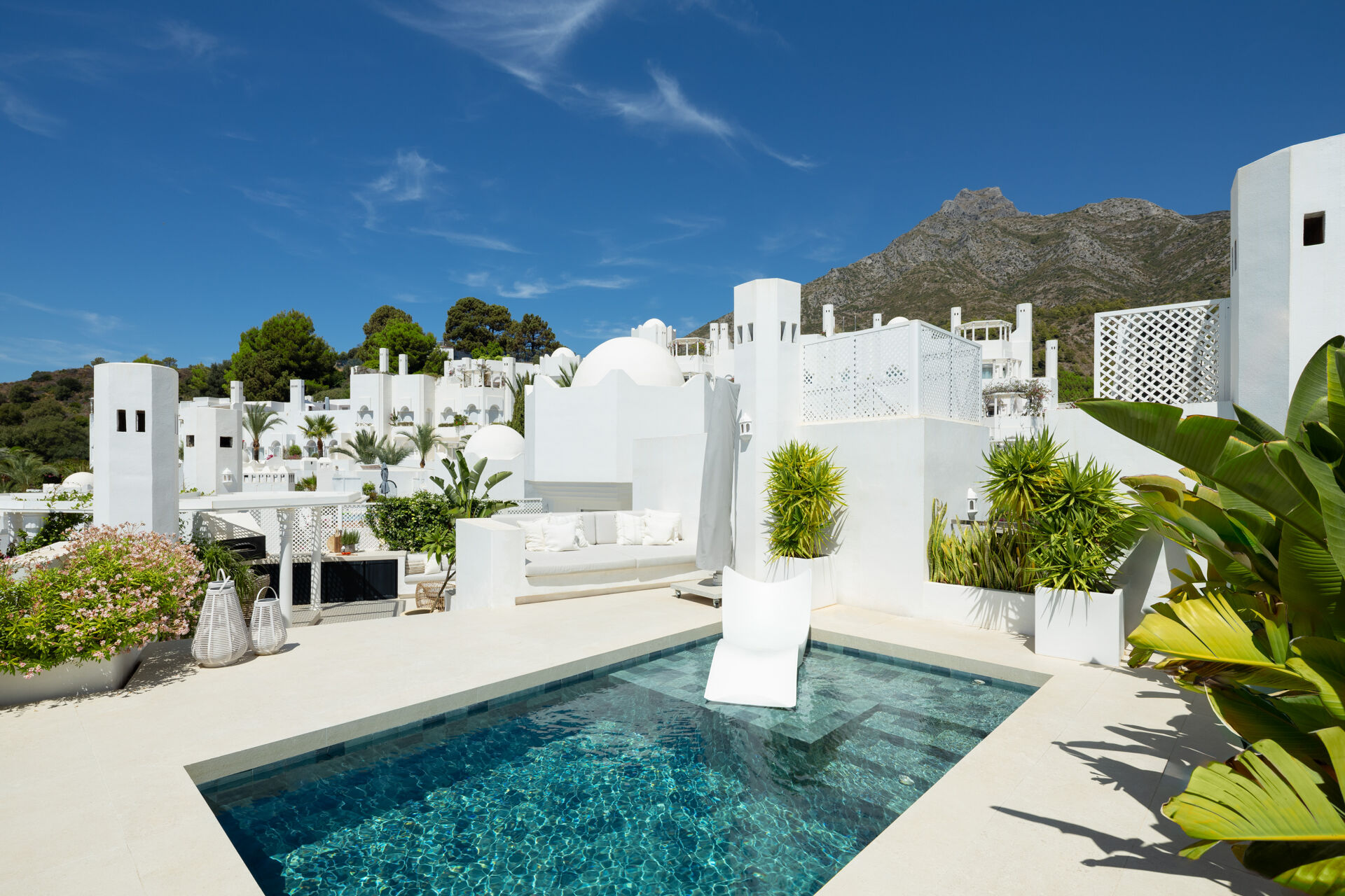 The pool on the roof terrace, with a sun lounger on its shallow step and La Concha mountain behind the neighbouring buildings.