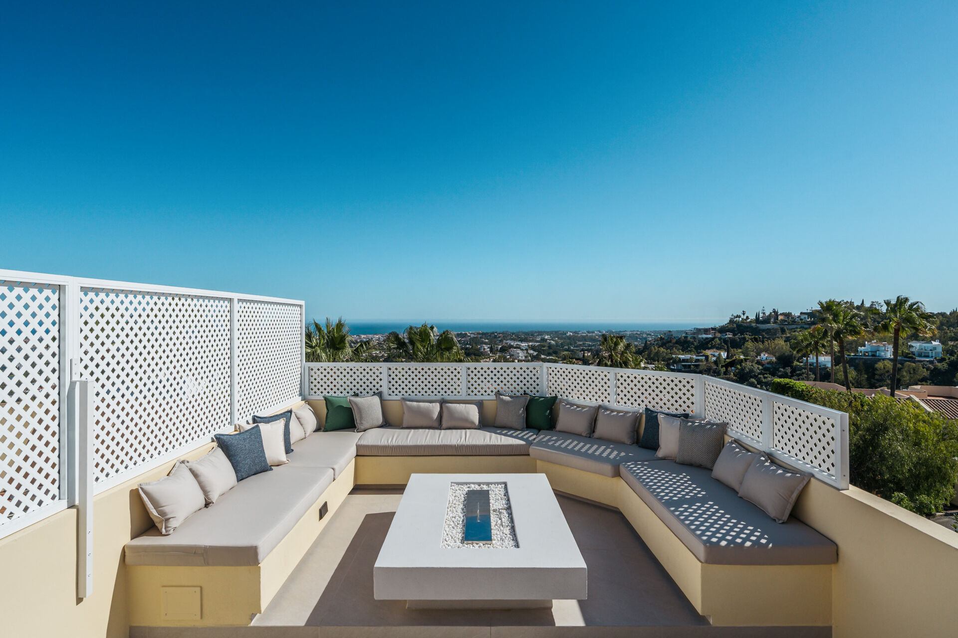 The roof solarium, with built-in seating around a fire table and a view over the rooftops to the sea.