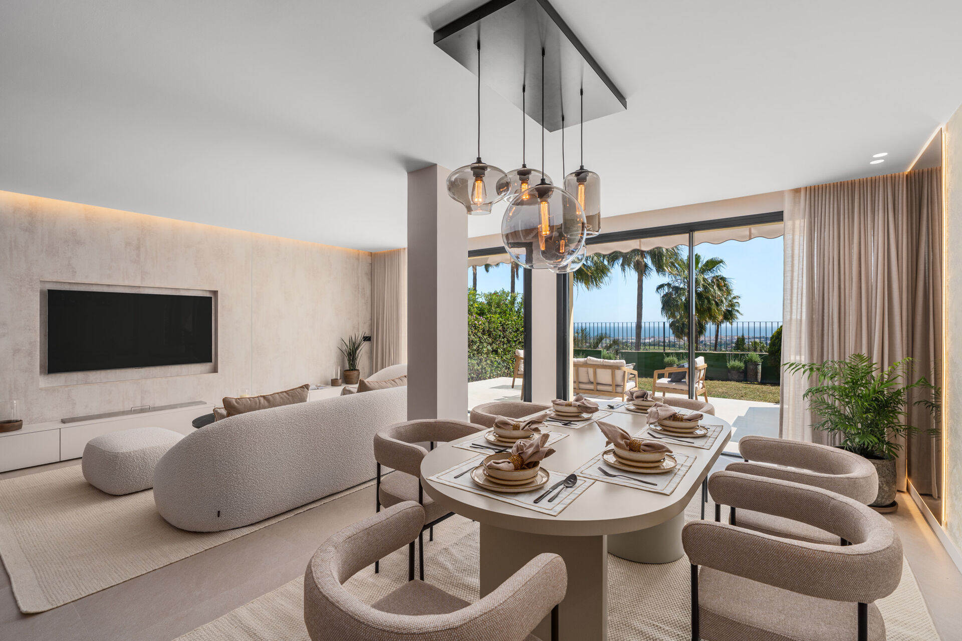 The dining table and the living area, with a curved sofa and glass doors onto the garden terrace.