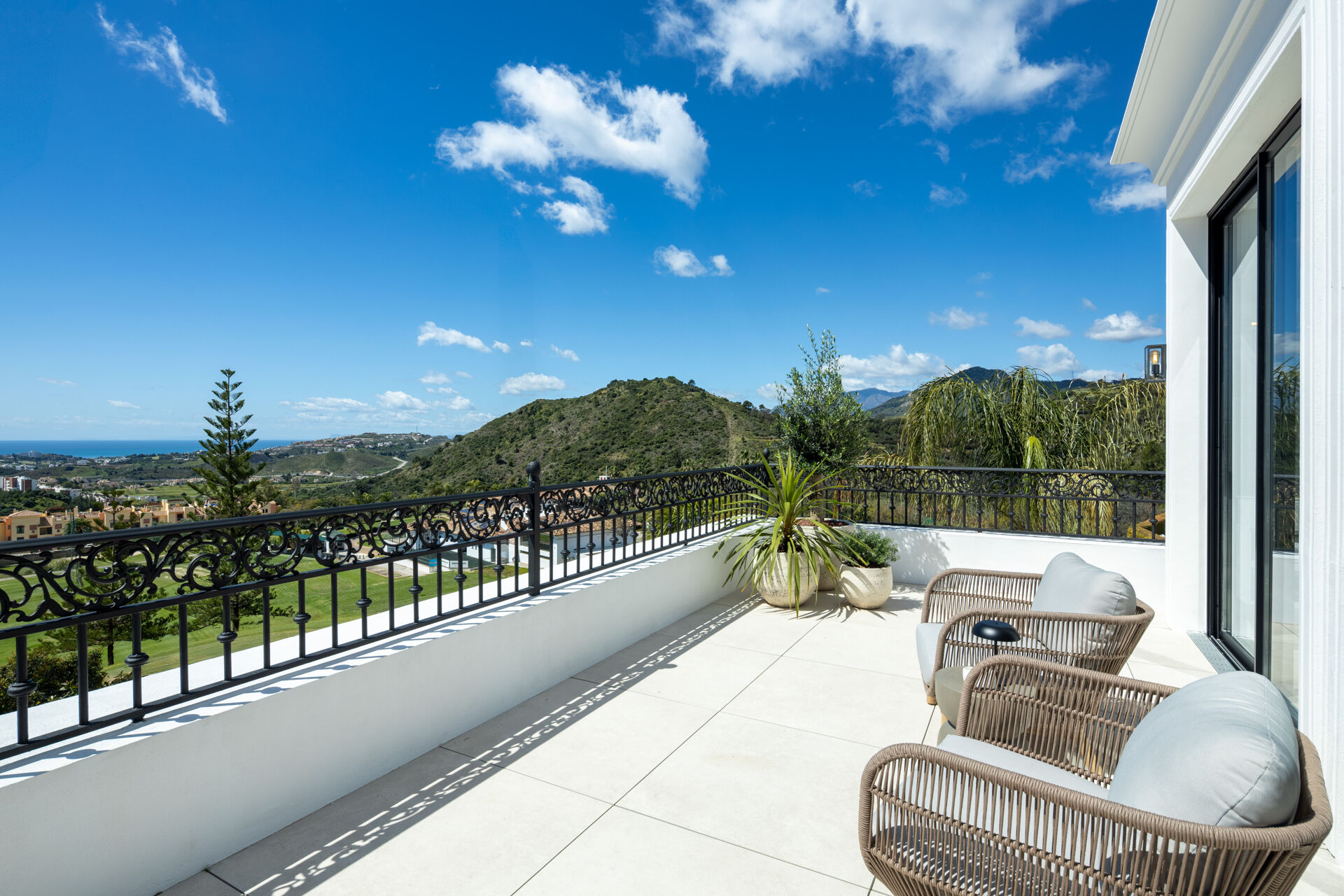 The upper terrace with wrought-iron railings, looking over a golf course and the hills towards the sea.