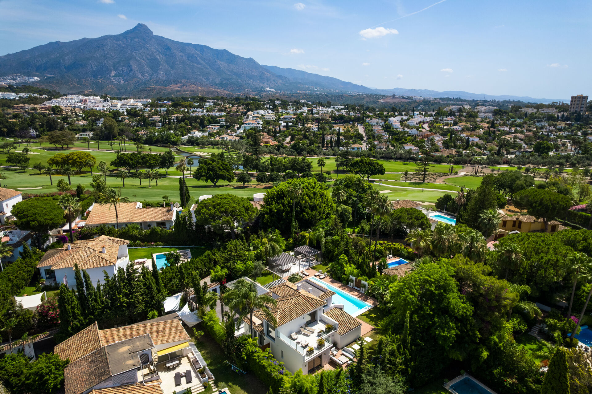 An aerial view over the neighbouring houses and a golf course, with La Concha mountain behind.