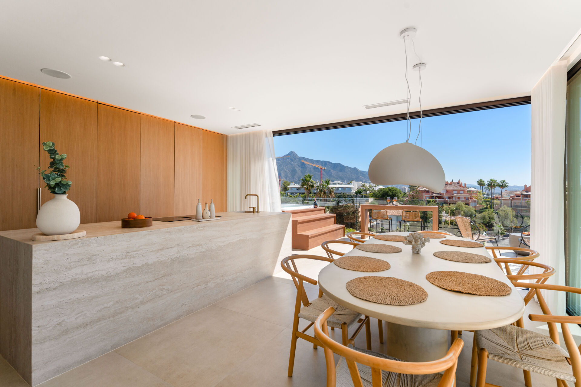 The kitchen island and the dining table in the open-plan living area, with a large glass opening towards the terrace.